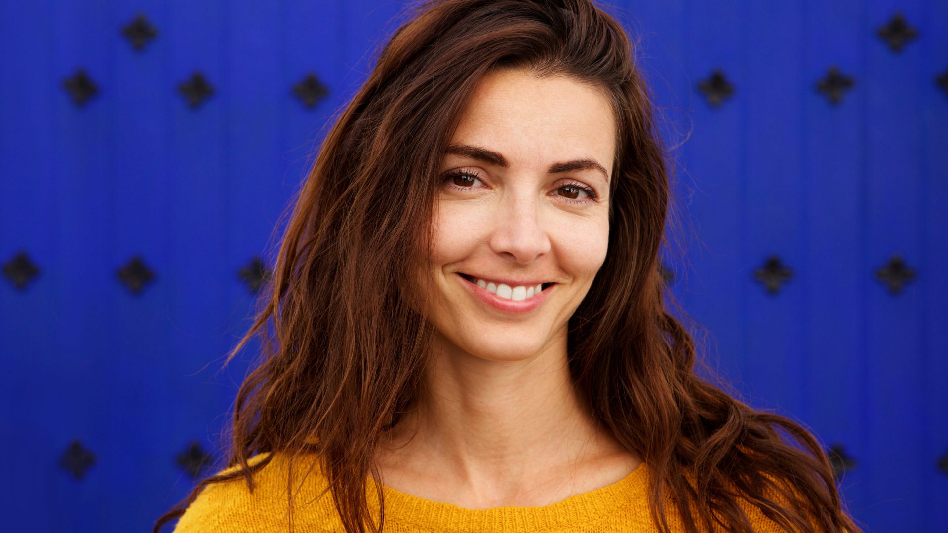 Close up portrait of beautiful young woman smiling against blue background